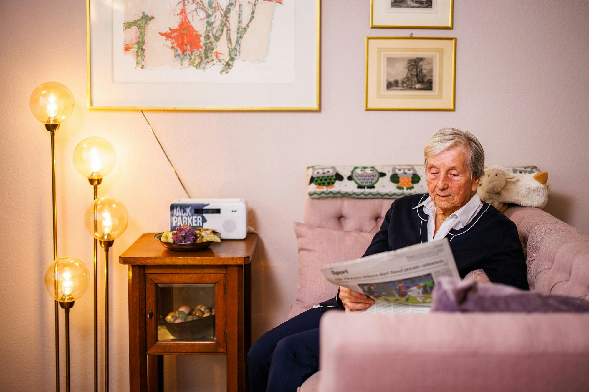 Älterer Mann liest Zeitung im gemütlichen Wohnzimmer.